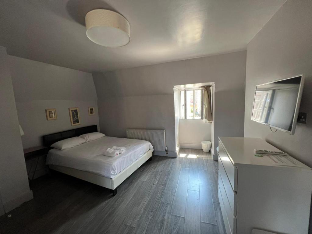 um pequeno quarto com uma cama e uma janela em Petticoat Accommodations em Londres