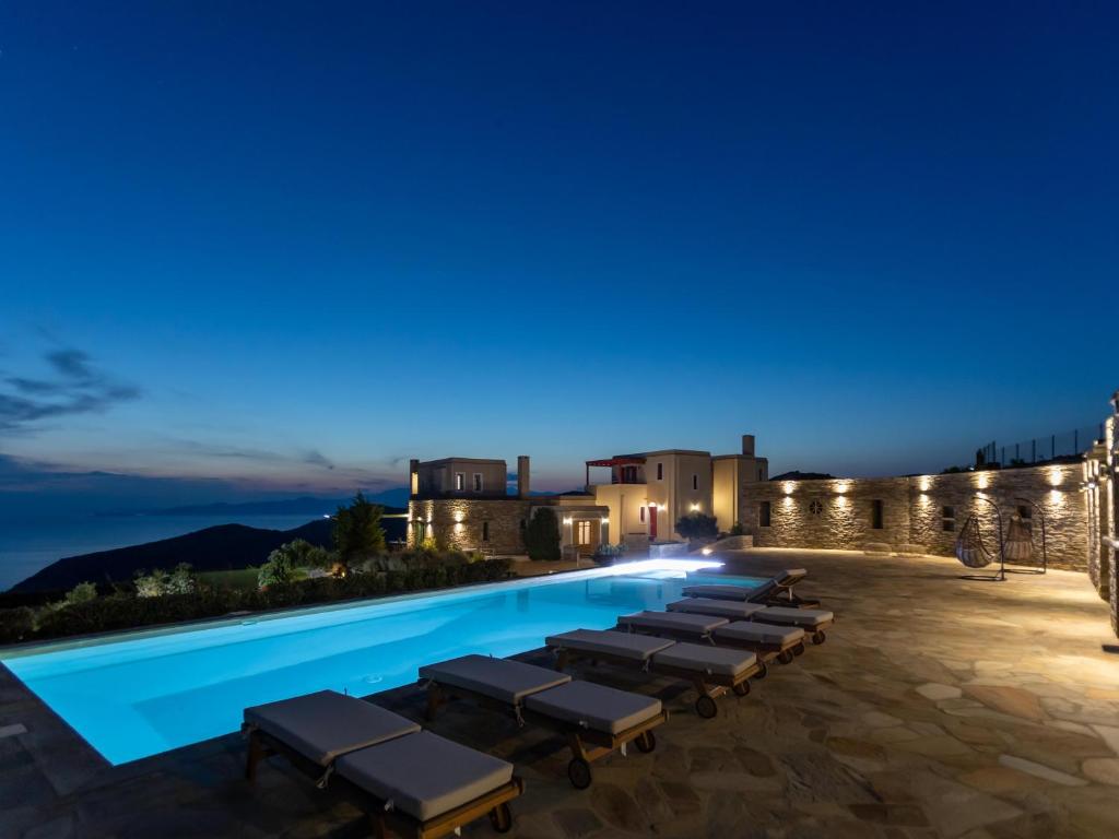 uma piscina à noite com uma fila de espreguiçadeiras em Bella Resorts Andros em Andros