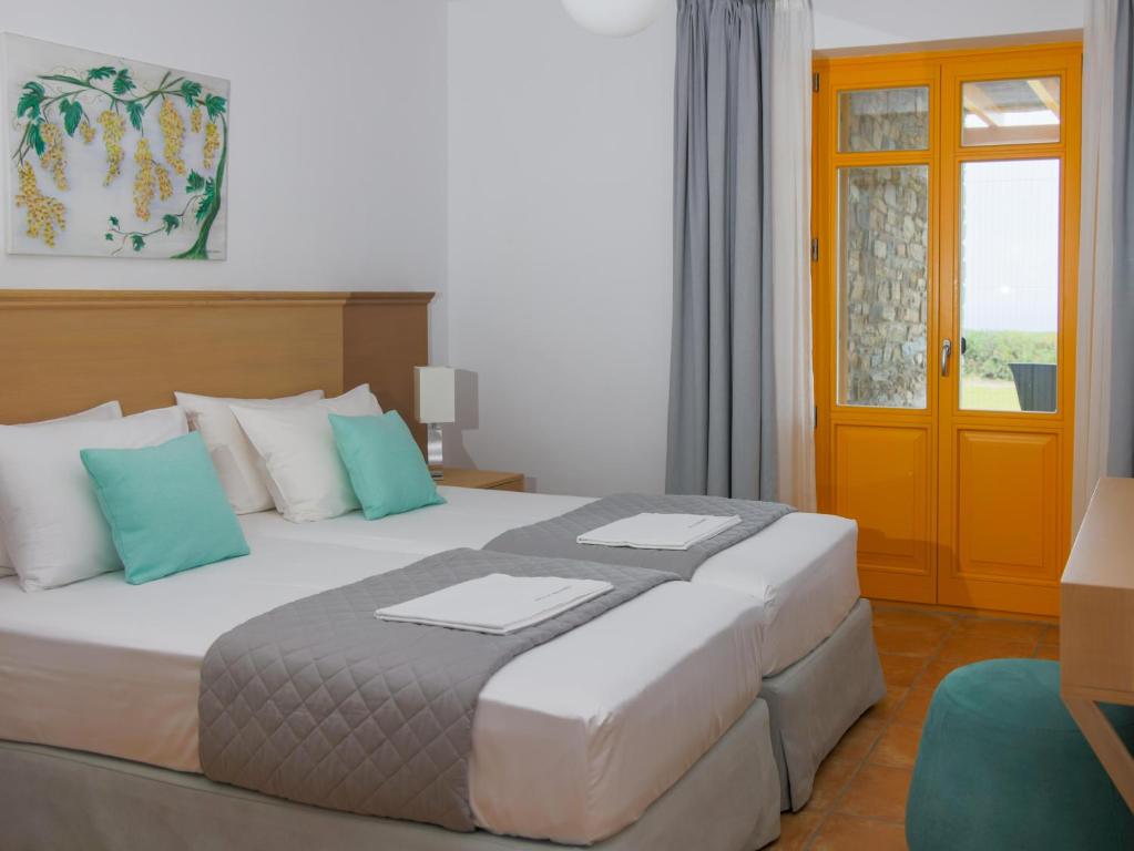 a bedroom with a large bed with blue and white pillows at Bella Resorts Andros in Andros