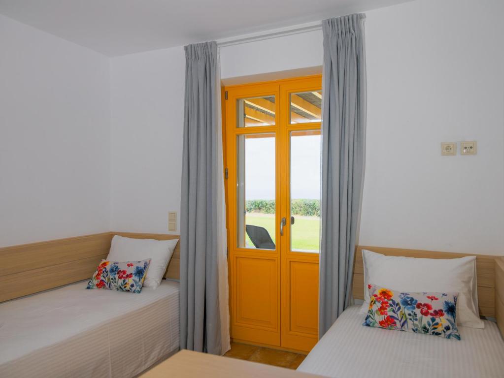 a room with two beds and a orange door at Bella Resorts Andros in Andros