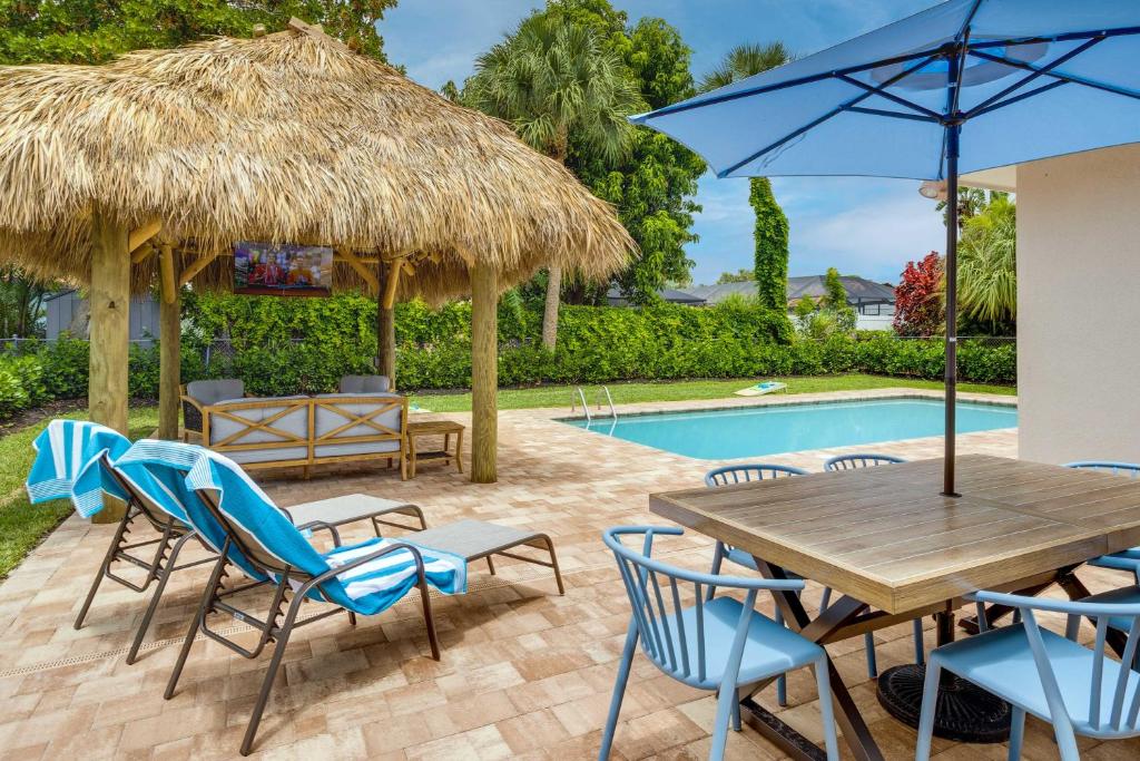 une terrasse avec une table, des chaises et une piscine dans l'établissement Modern Palm Beach Gardens Home with Private Pool, à Palm Beach Gardens
