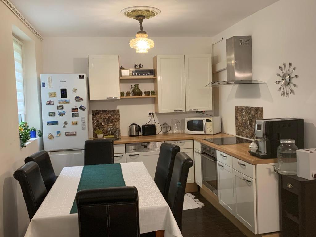 uma cozinha com armários brancos e uma mesa com cadeiras em Apartament 3 camere Joy em Ocna-Mureşului