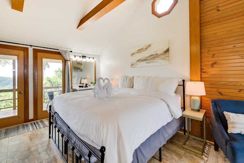 1 dormitorio con 1 cama blanca grande y 1 silla en Eureka Springs Cabin Rental about 5 Mi to Beaver Lake! en Garfield
