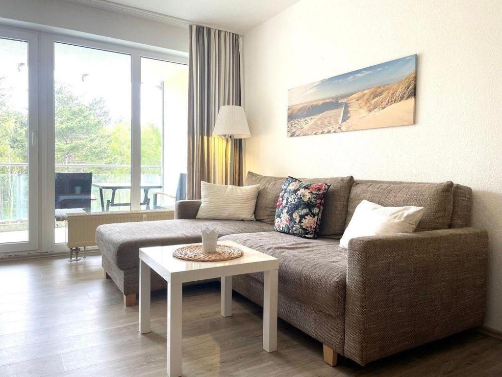 ein Wohnzimmer mit einem Sofa und einem Tisch in der Unterkunft Strandhaus Nordseebrandung Fewo B4.1 in Cuxhaven