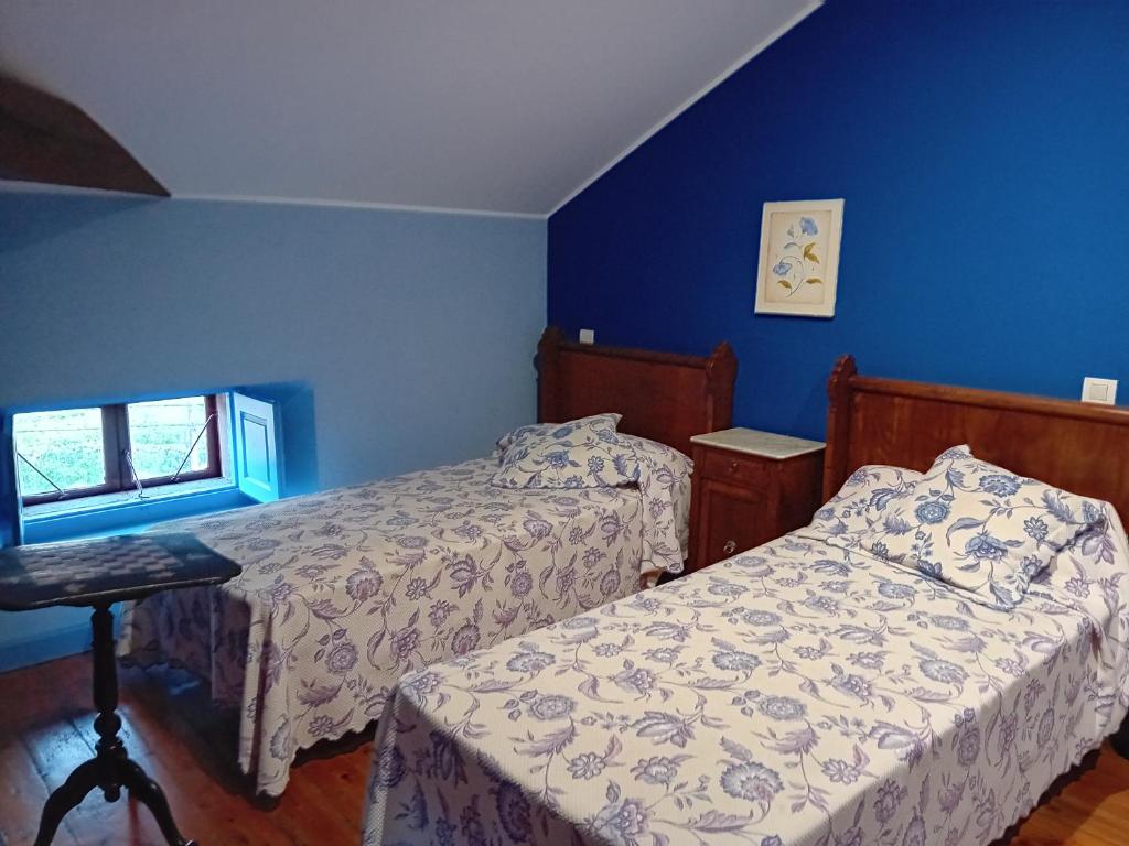 um quarto com 2 camas e uma parede azul em Casa Los Lomas em Arenas de Iguña