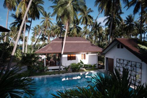 una casa y una piscina frente a un edificio en Coconut Tree Homestay, en Ban Wa Thon