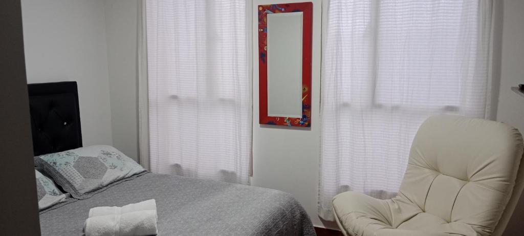 a bedroom with a bed and a chair and a mirror at Dulce hogar baño compartido in Chía