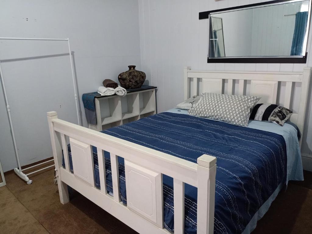 a white bed with a blue comforter and a mirror at Spacious Suite in Townsville