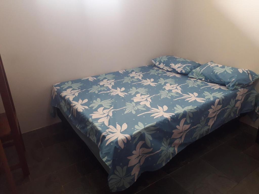 a bed with a blue blanket with flowers on it at AP DA FABY in Barra de São Miguel