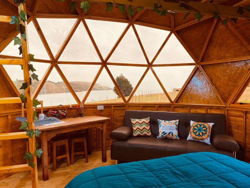 Habitación con sofá y ventana en un iglú en Lago De Tota Glamping, en Tota