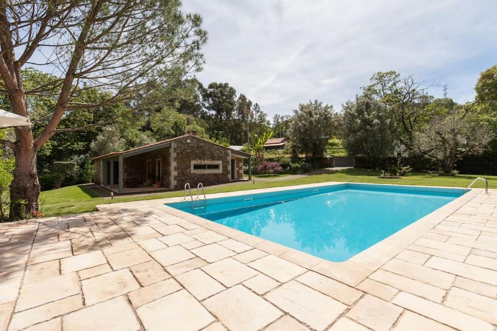 una piscina en un patio con una casa en Quinta dos Castanheiros Piscina e Jardim privado, en Ponte de Lima