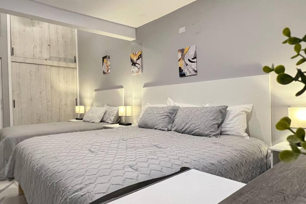 a white bedroom with two beds and two lamps at Habitación Plata #2 in Aguascalientes