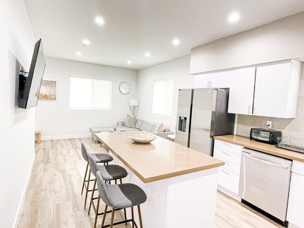una cocina con armarios blancos y una isla de cocina con taburetes en Stylish 4 Bedroom Townhouse in Mid City en Los Ángeles