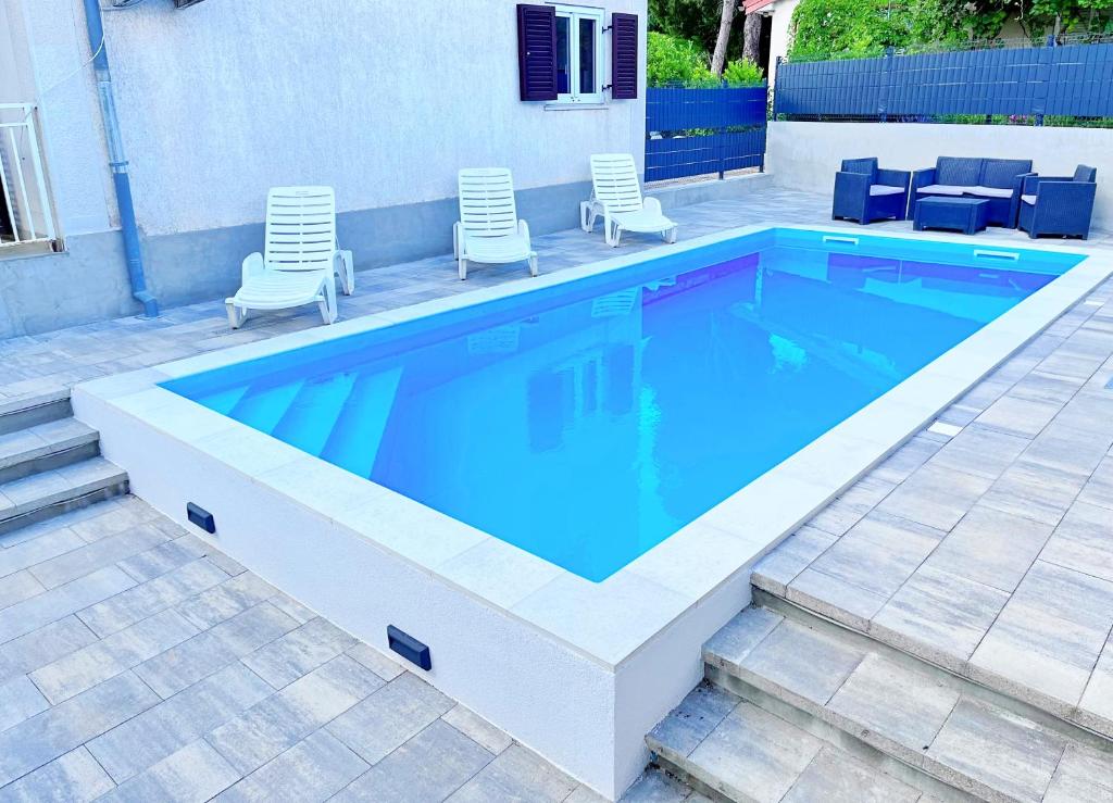 a swimming pool with blue water in a backyard at Adria Holiday Home in Pinezici
