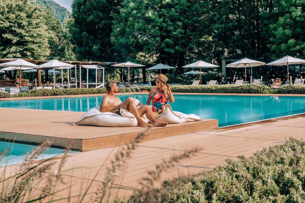 twee personen op kussens naast een zwembad bij Sheraton Lake Como Hotel in Como