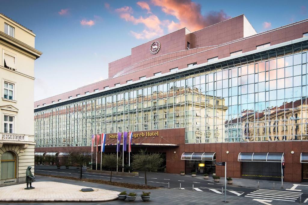 a large glass building with a person walking in front of it at Sheraton Zagreb Hotel in Zagreb