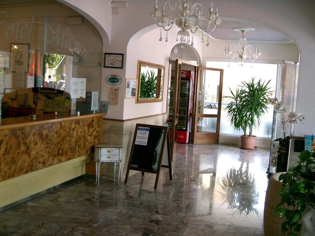 a store lobby with a counter and a chandelier at Hotel Maxim in Caorle