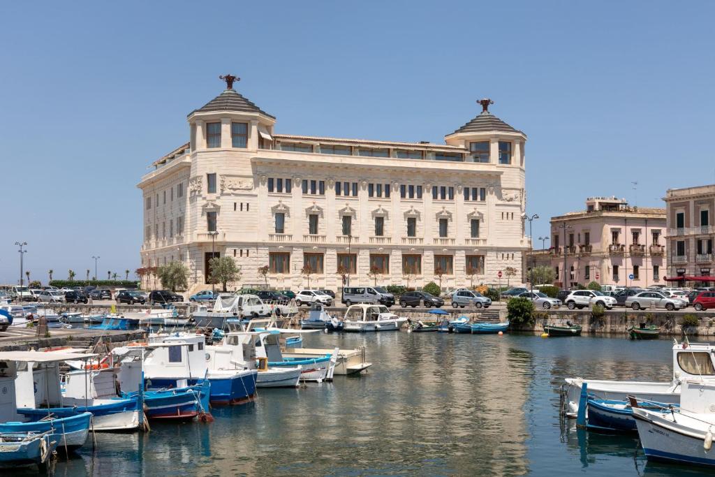 a group of boats in a marina in front of a building at Ortea Palace Hotel, Sicily, Autograph Collection in Siracusa