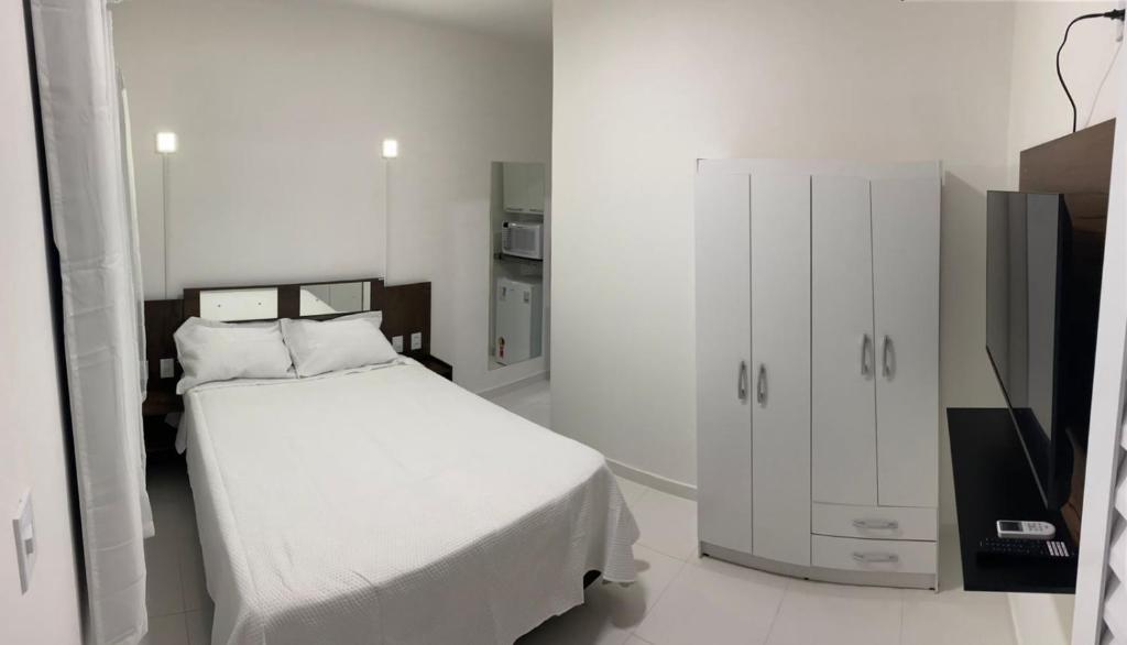 a white bedroom with a bed and a tv at Pousada Tropical Paulo Afonso in Paulo Afonso