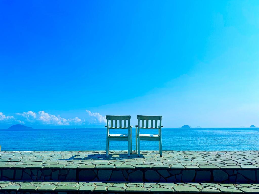 two chairs sitting next to the ocean at なにもない幸せな島のリトリート宿 The Bonds in Matsuyama
