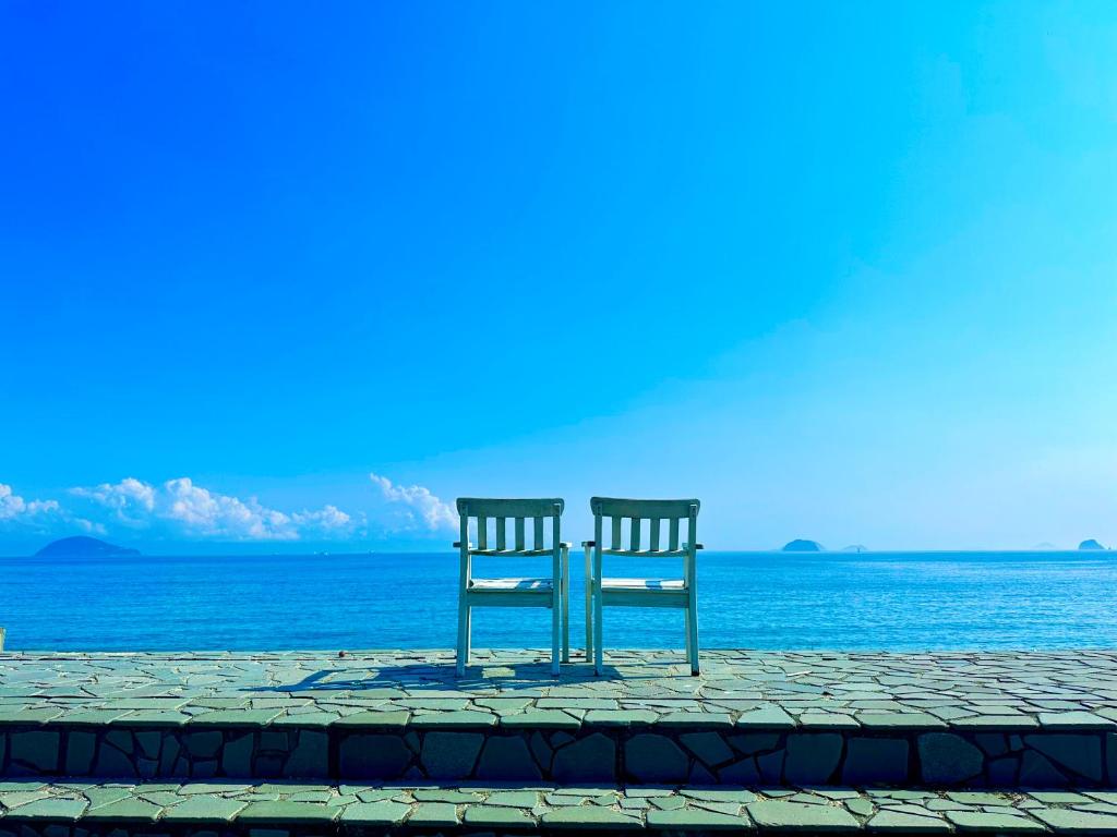 due sedie sedute accanto all'oceano di なにもない幸せな島のリトリート宿 THE BONDS Island Stay a Matsuyama