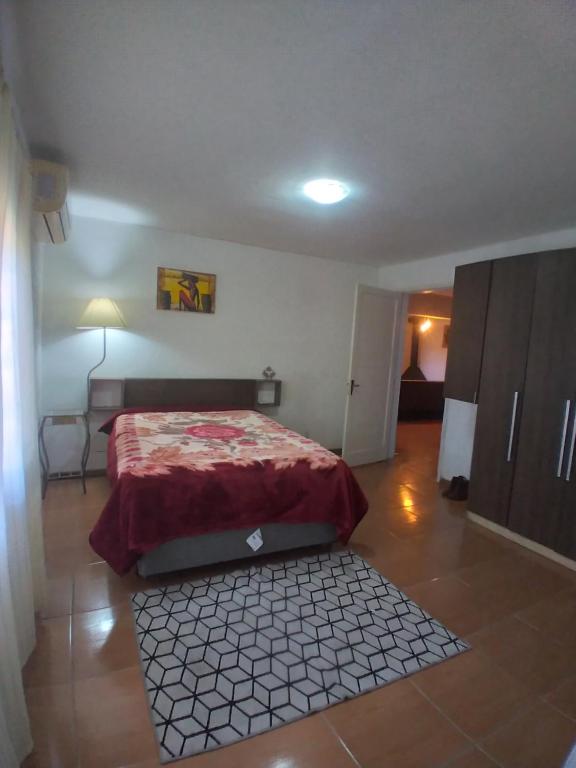 1 dormitorio con 1 cama con colcha roja. en Casa com piscina Laranjal, en Pelotas