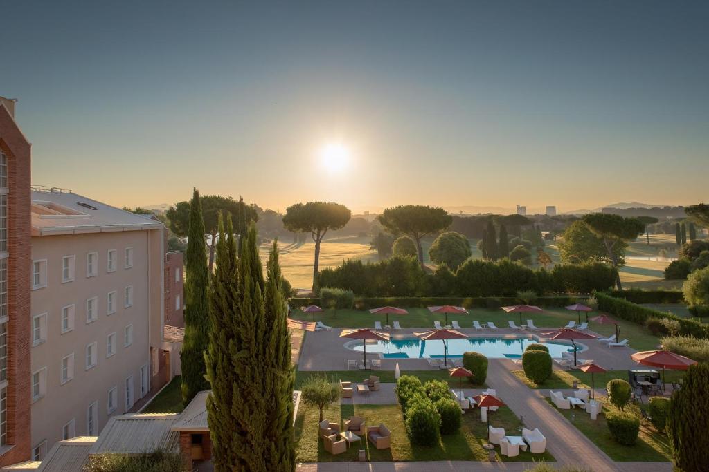 a view of a resort with a pool and a sunset at Sheraton Rome Parco de Medici in Rome