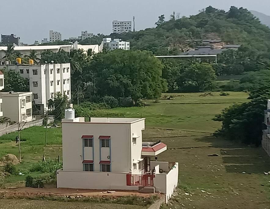 un pequeño edificio blanco en un campo con edificios en Sathya Sai Nivas, en Puttaparti