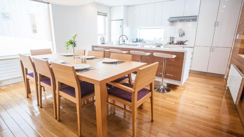 Il comprend une cuisine et une salle à manger avec une table et des chaises en bois. dans l'établissement Ezo Yume Chalet, à Niseko
