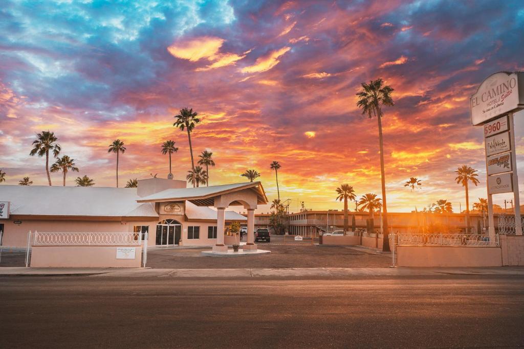 um edifício com palmeiras em frente a um pôr-do-sol em El Camino Hotel & Suites em Heroica Caborca