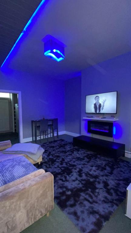 a purple room with a bed and a flat screen tv at Imperial Suites in Bradford