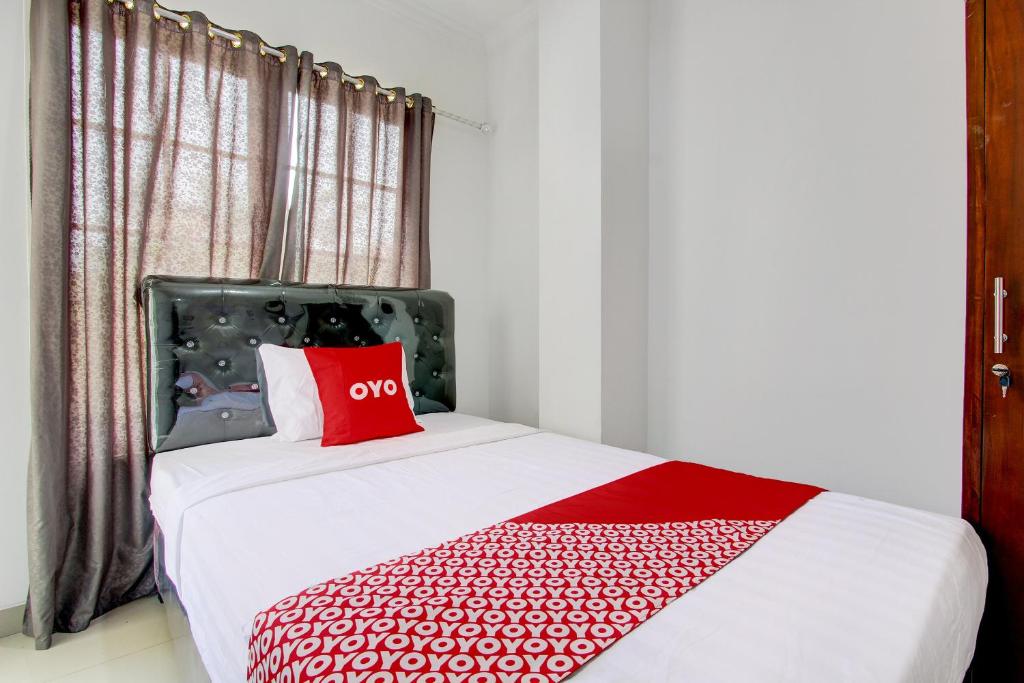 um quarto com uma cama com uma almofada vermelha em OYO 92479 Pasadena House em Semarang