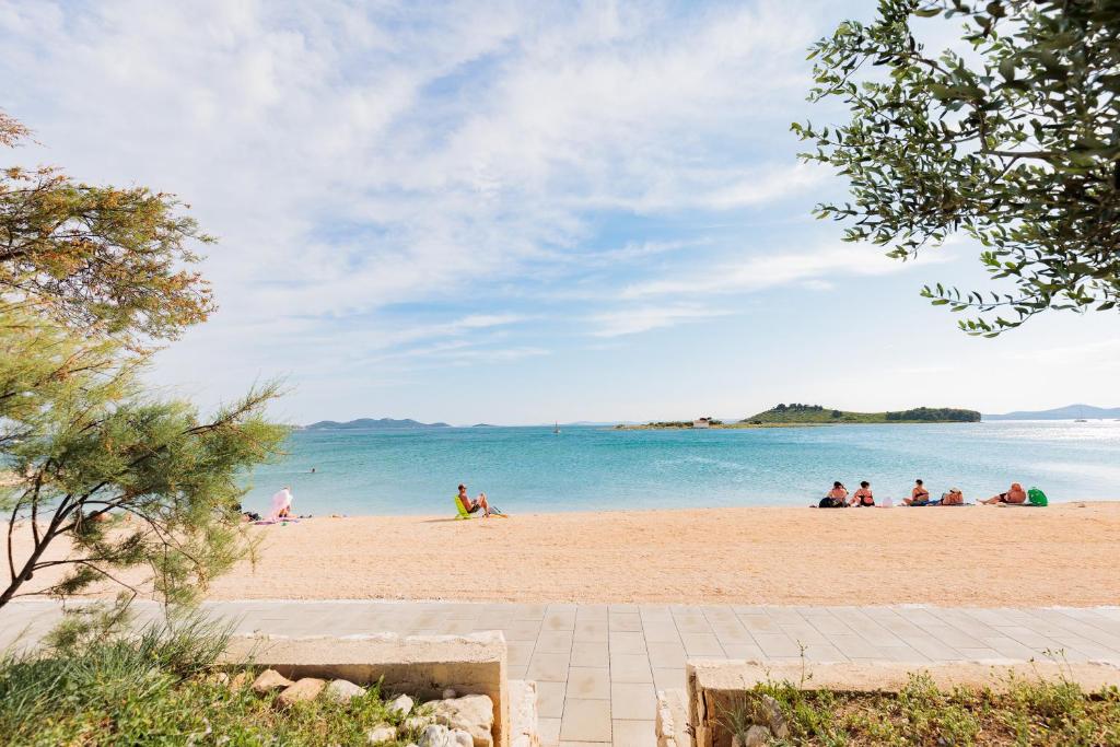 a group of people sitting on a beach at NEW!!! Luminose beach house in Pakoštane