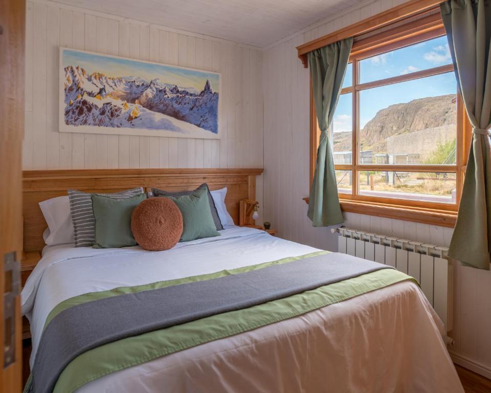 um quarto com uma cama grande e uma janela em Pitihué Aparts em El Chaltén