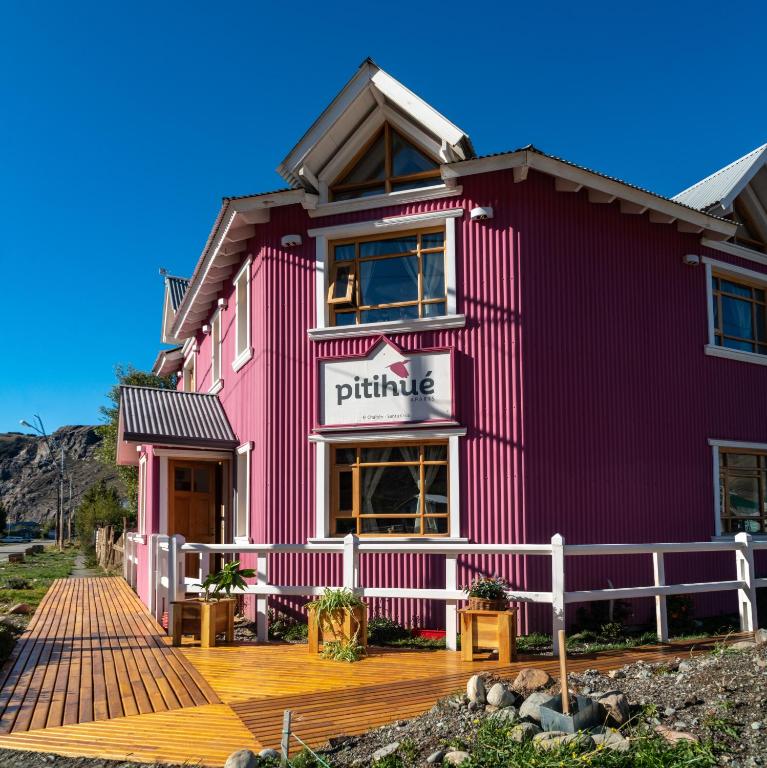 a pink building with a wooden deck in front of it at Pitihué Aparts in El Chalten