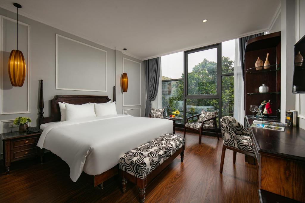 1 dormitorio con 1 cama blanca grande y escritorio en Salute Premium Hotel & Spa en Hanoi