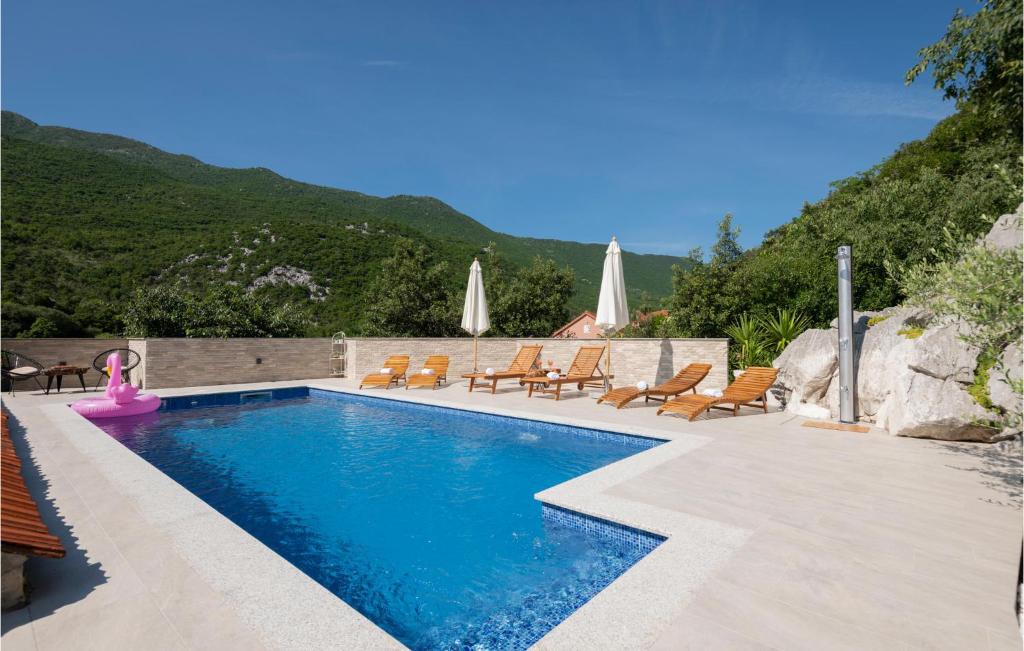 una piscina con tumbonas y una montaña en Stunning Home In Vrgorac With Kitchen, en Vrgorac