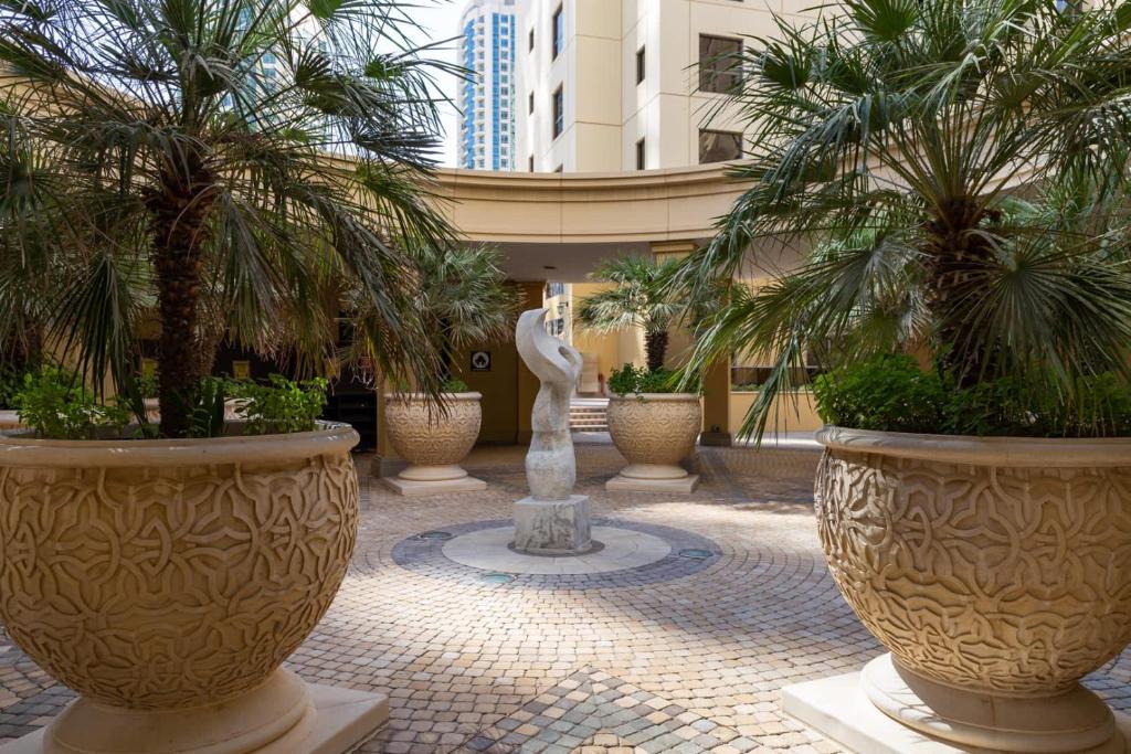 a courtyard with palm trees and a statue in a building at Murjan 2 in Dubai