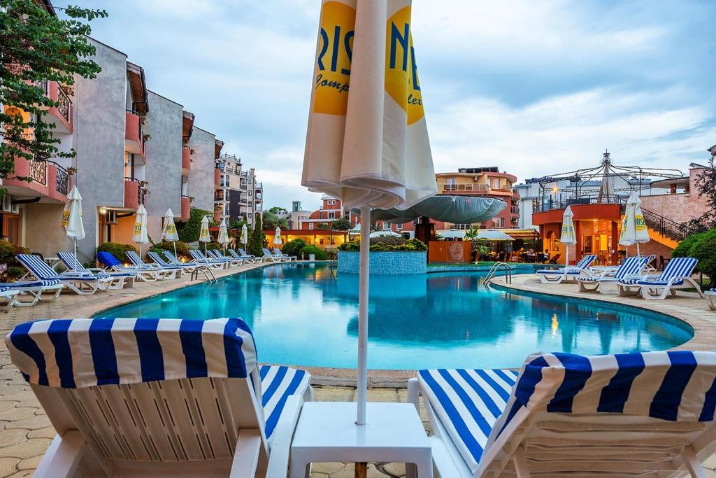 a swimming pool with two chairs and an umbrella at Complex Sunrise by HMG - All Inclusive in Sunny Beach