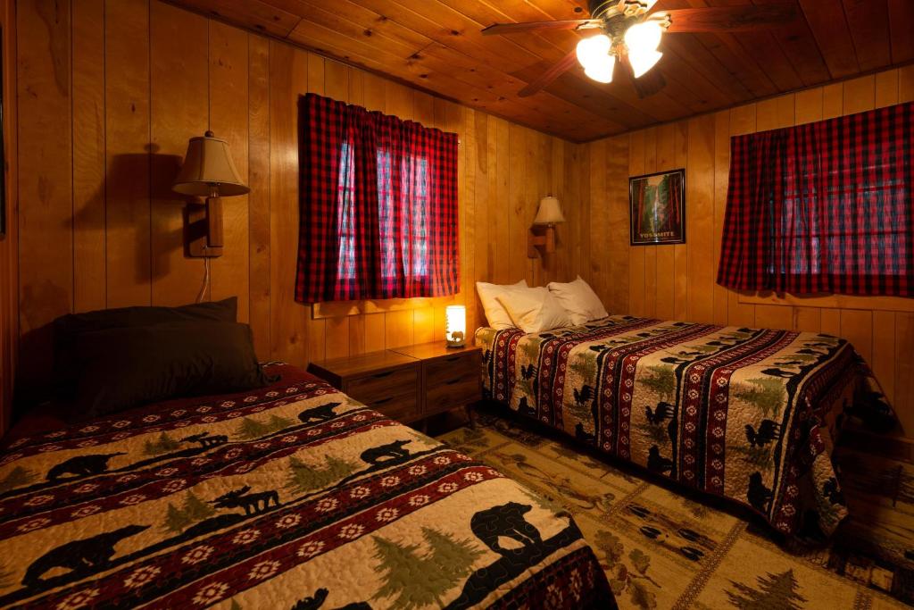 two beds in a room with wooden walls and windows at Along The River in Yosemite West