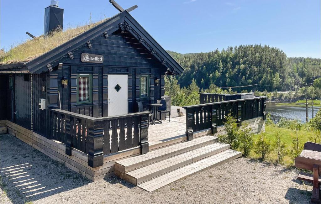 uma cabana preta com um alpendre e escadas ao lado de um lago em Amazing Home In Mykland With Kitchen em Mykland