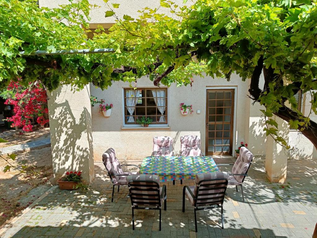 un patio con mesa y sillas bajo un árbol en The Grapevine Guest House, en Pafos