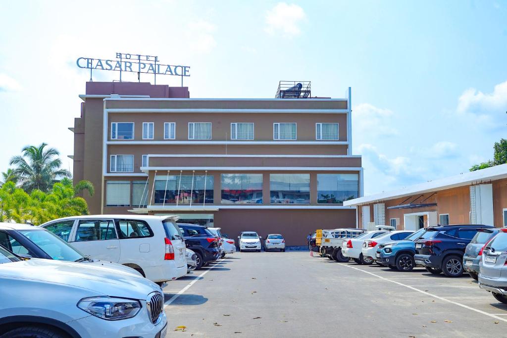 un edificio con coches estacionados en un estacionamiento en HOTEL CEASAR PALACE en Kottayam