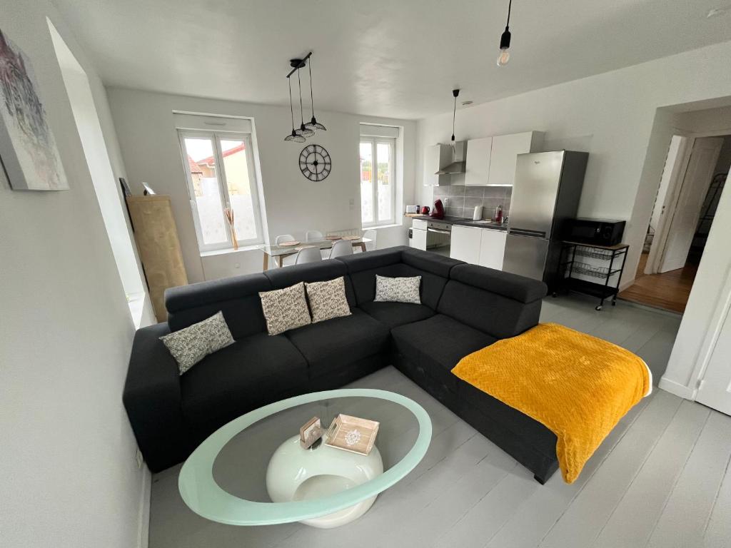 a living room with a black couch and a table at Gîte de la gare - avec parking in Hesdigneul-lès-Boulogne