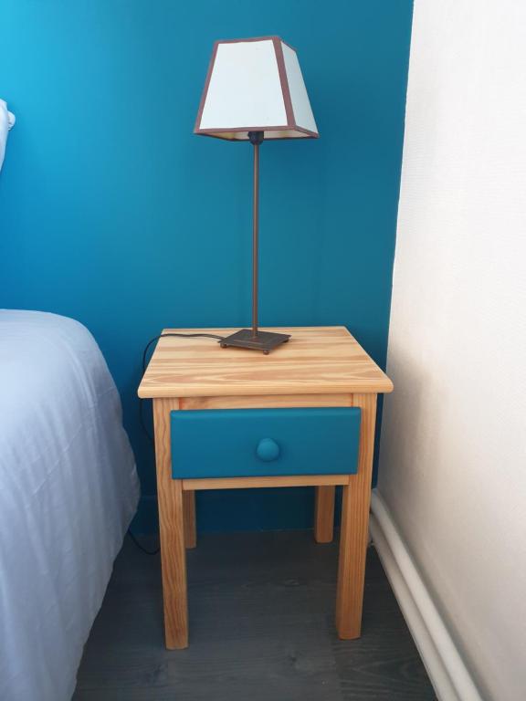 a table with a lamp on it next to a bed at Chambre individuelle Jules in Agen