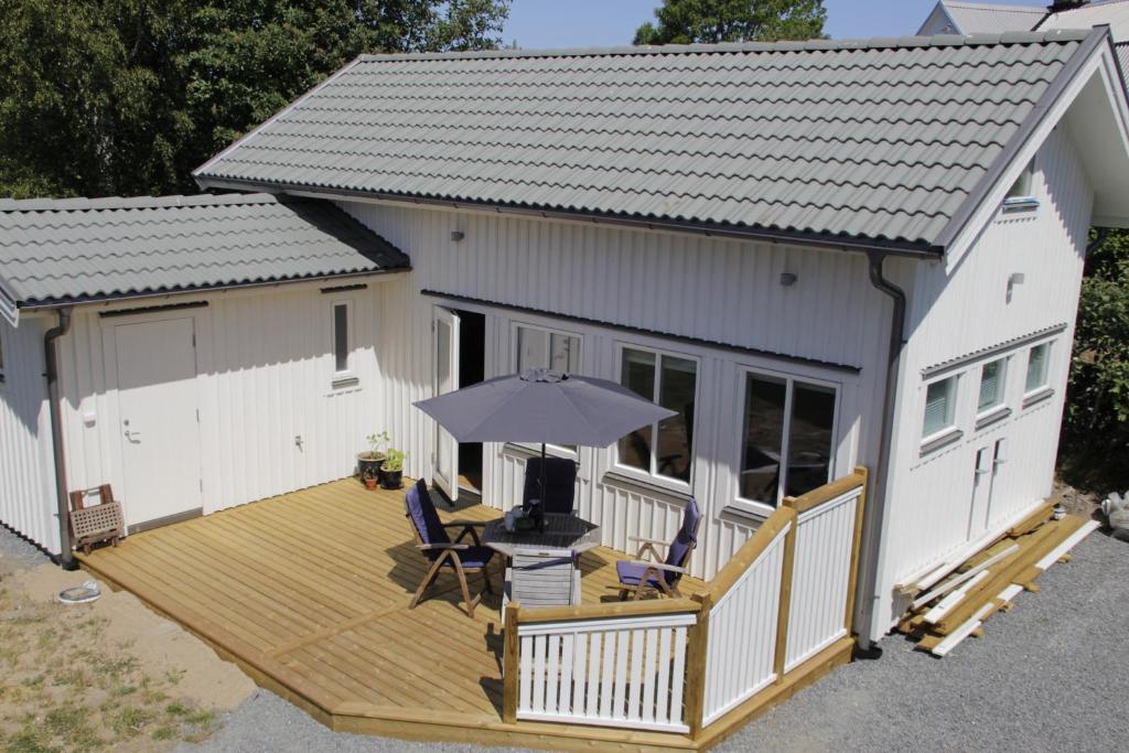 a house with a wooden deck with an umbrella at Fräsch nybyggd stuga på Getterön Varberg in Varberg