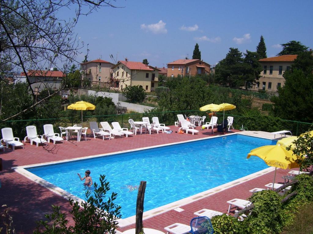 einen Pool mit Stühlen und Sonnenschirmen in der Unterkunft Holiday Home in Paciano with Swimming Pool Terrace Billiards in Paciano