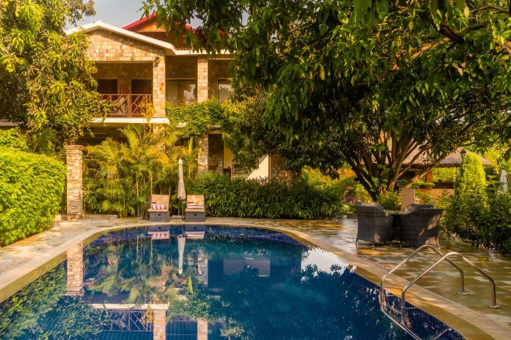una piscina frente a una casa en Tree of Life Vanvilas Riveredge Corbett en Rāmnagar