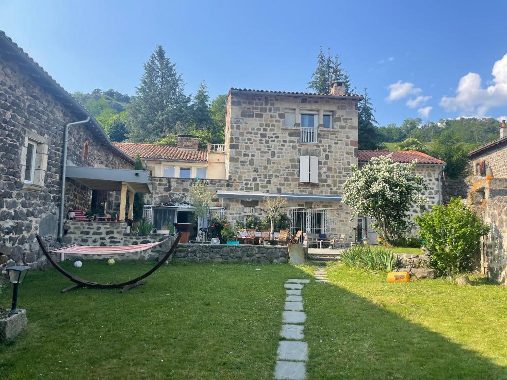 a stone house with a yard with a hammock at Ferme rénovée avec Piscine in Polignac