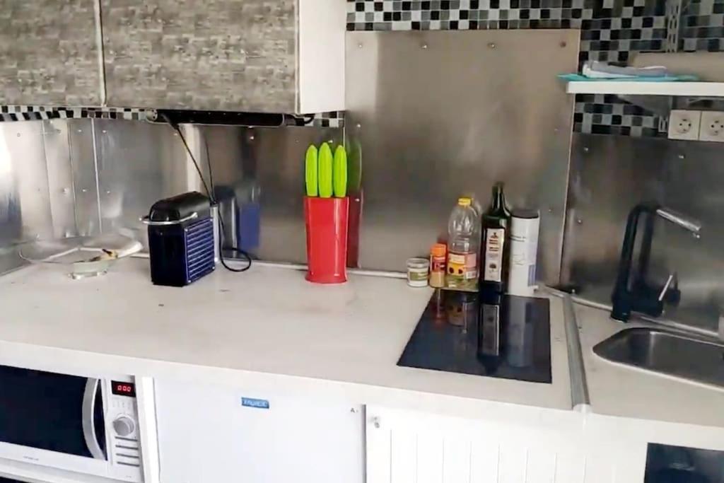 eine Küchentheke mit Spüle und eine Tasse mit grünen Utensilien in der Unterkunft Studio meublé vue tour Eiffel et tout Paris in Saint-Maurice